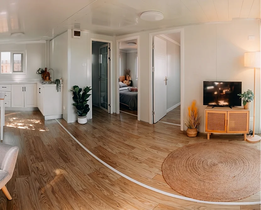 Prefab tiny home living room area with wooden floors and two bedroom doors